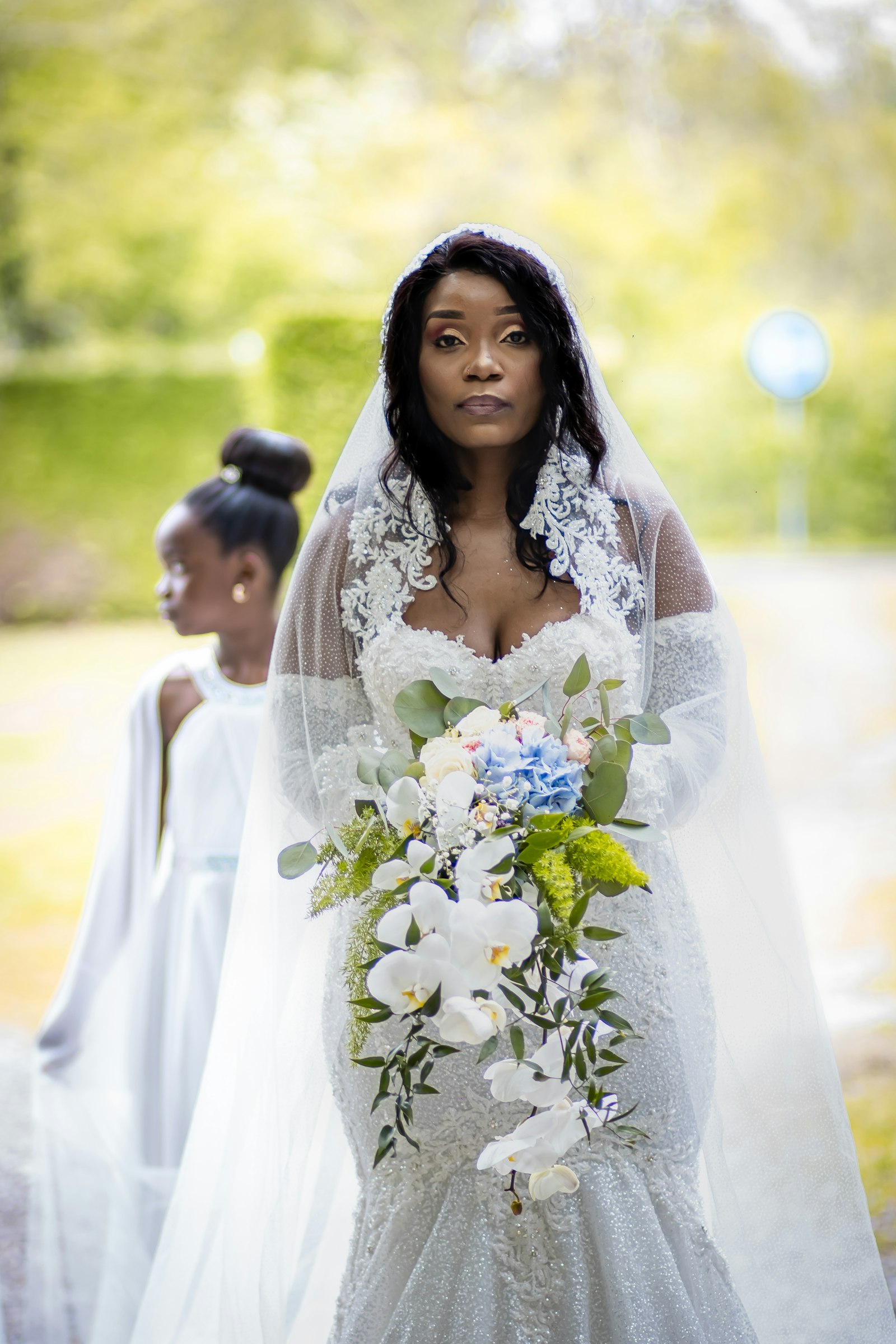 Bride from behind, cathedral veil trailing down a tree-lined path