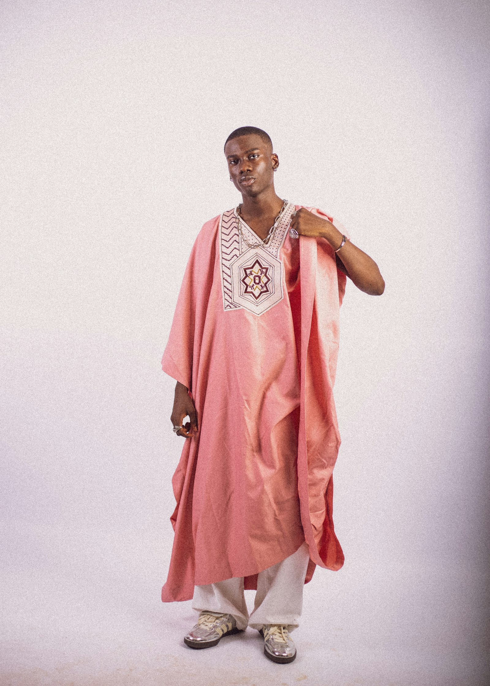 Rose agbada with an embroidered chest panel, on a blush wall